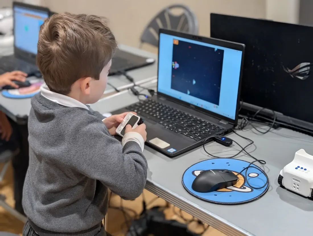 A child at a laptop steering a spaceship game they have built